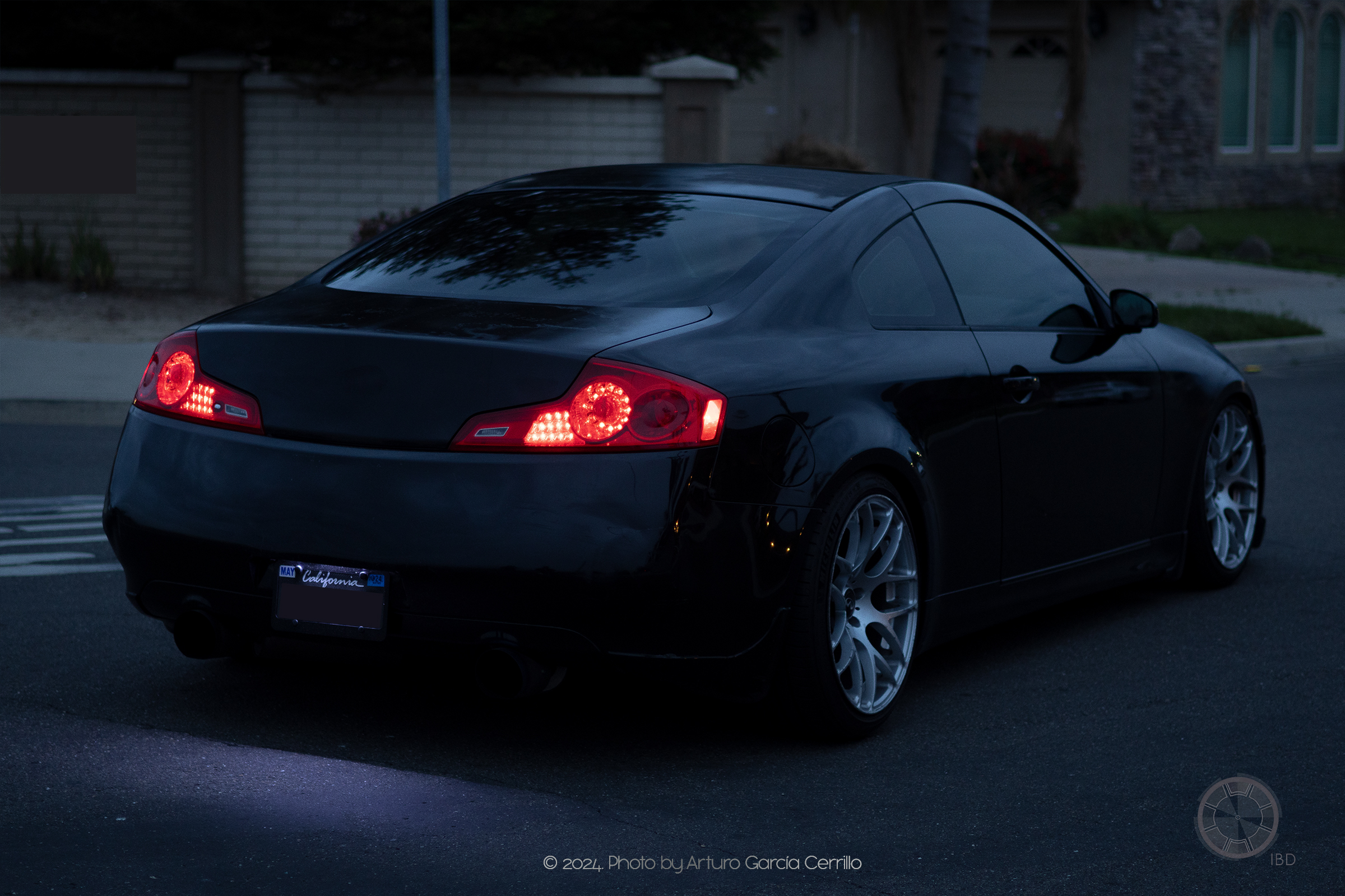 Picture of a black infinity car stopped in middle of street rear view