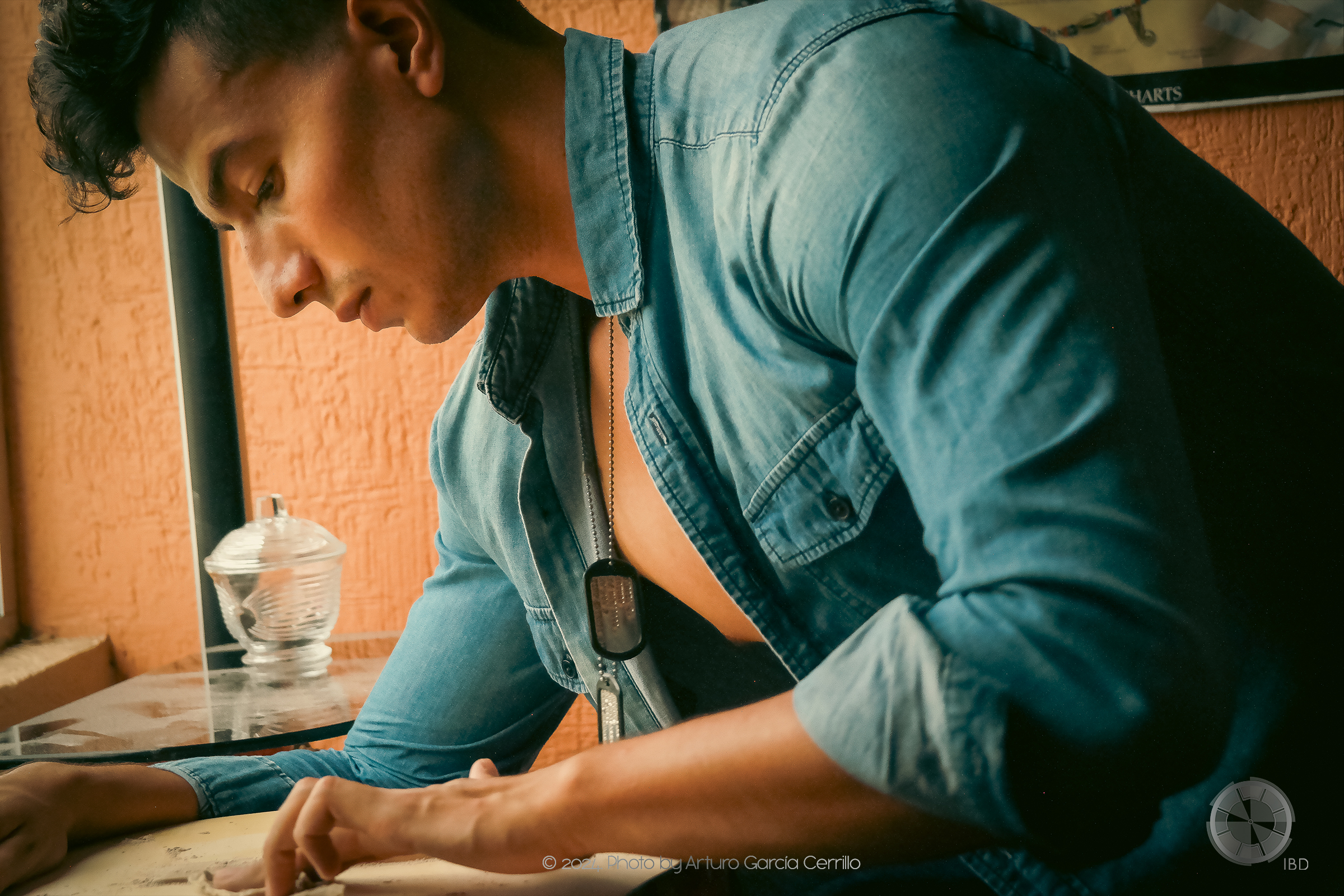 Picture of guy with blue long sleeve shirt sanding his yellow guitar.