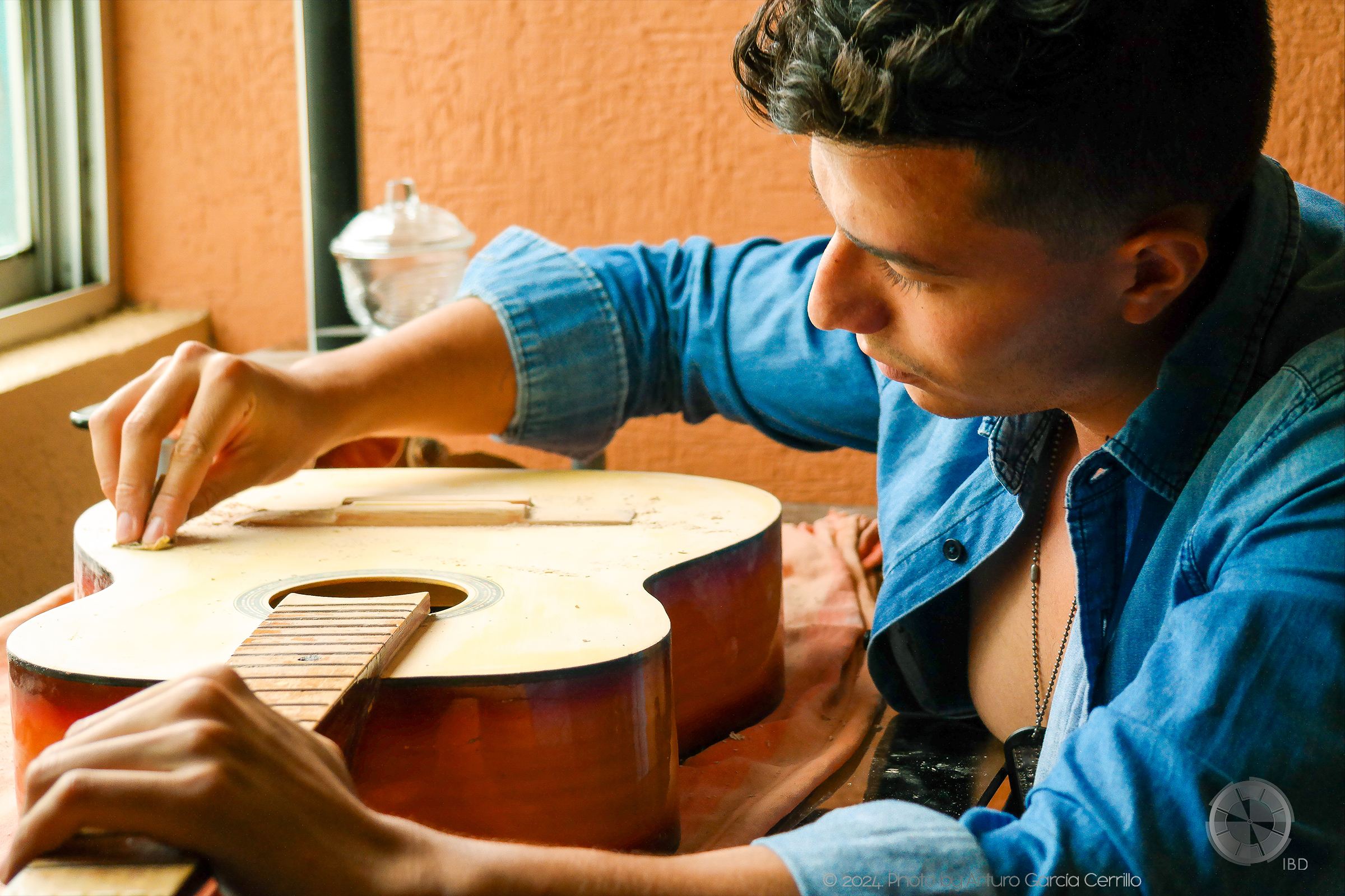 Picture of guy sanding his yellow guitar.