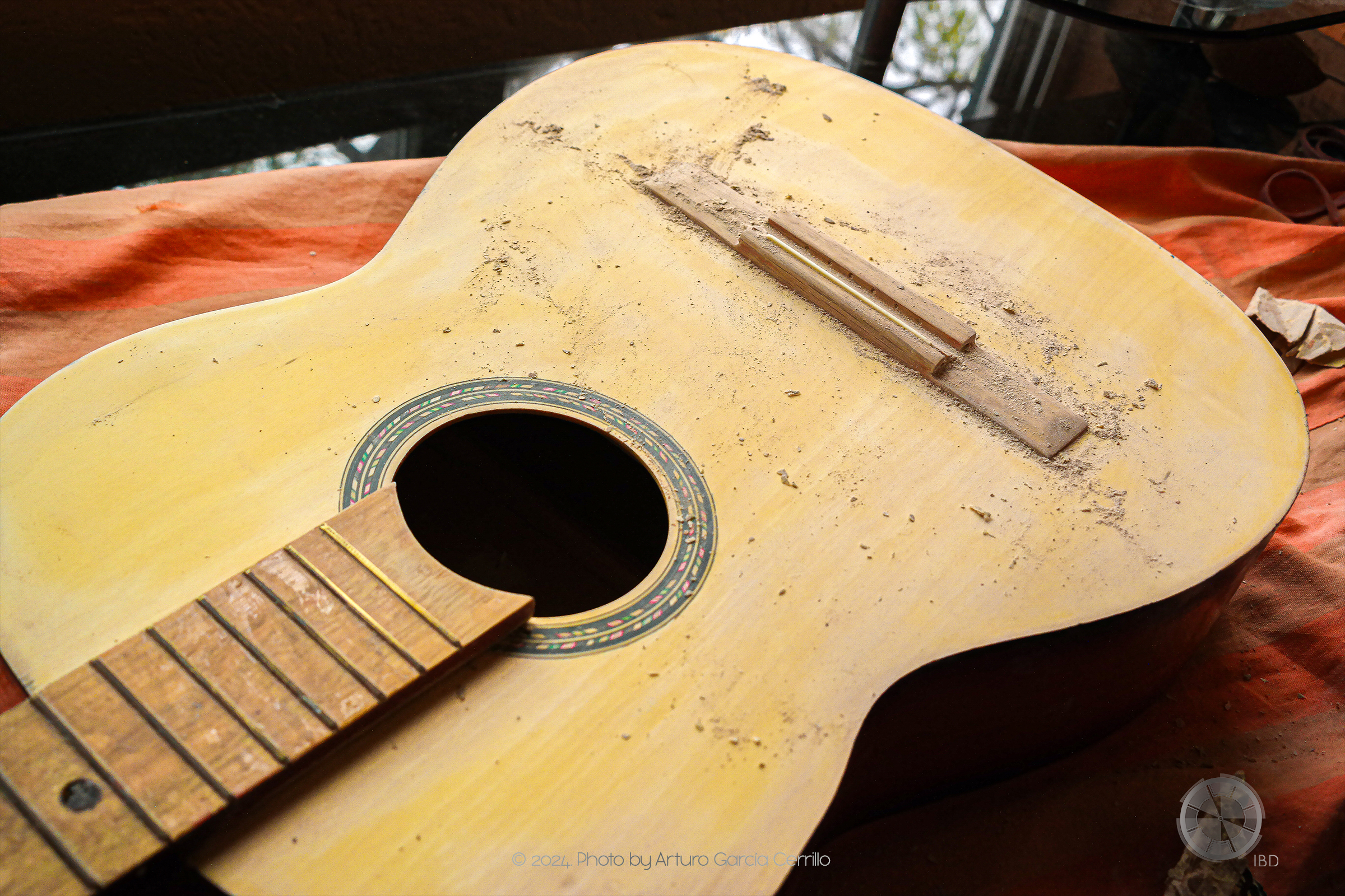 Picture of yellow acoustic guitar without strings. Residues of enamel resulting from sanding are shown.