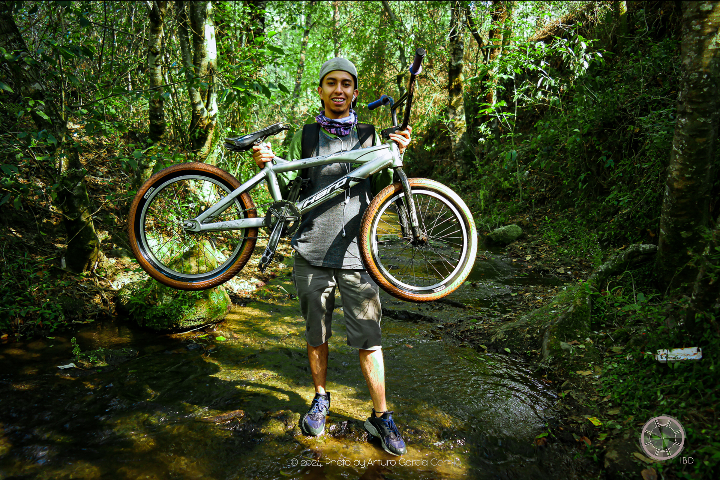 Portrait of guy holding BMX bycicle in the middle of the forest